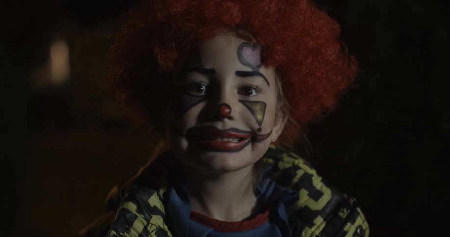 A child in a halloween costume is blinking their eyes and smiling