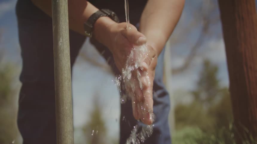A man washes his hands outdoors