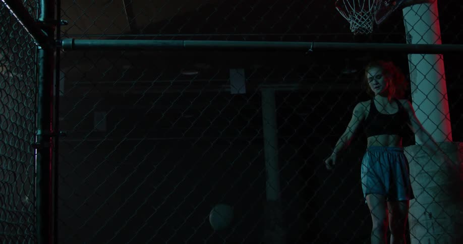 A female athlete throws a basketball at a fence