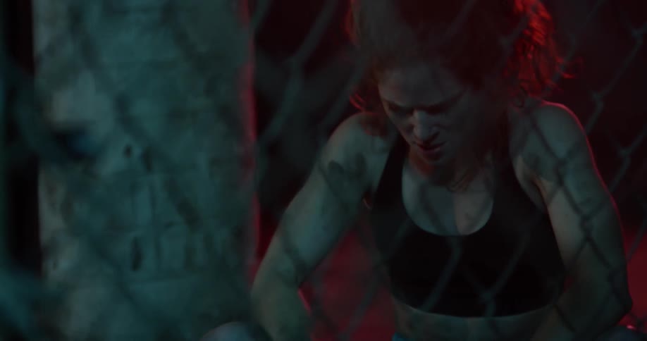 A woman exhales heavily sitting on a bench in a locker room