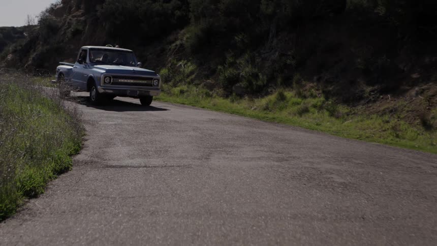A blue truck on a winding road in the daytime