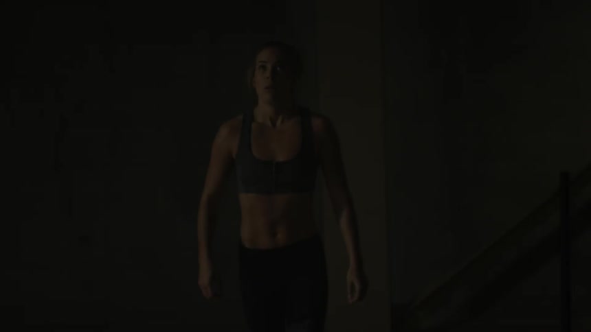 A woman pushes a weight rack in a gym
