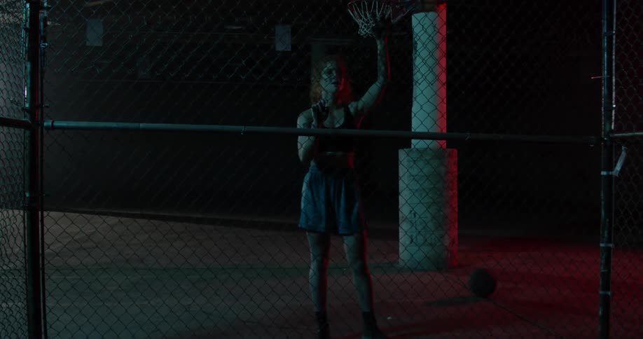 A female athlete leaning against a fence walks away