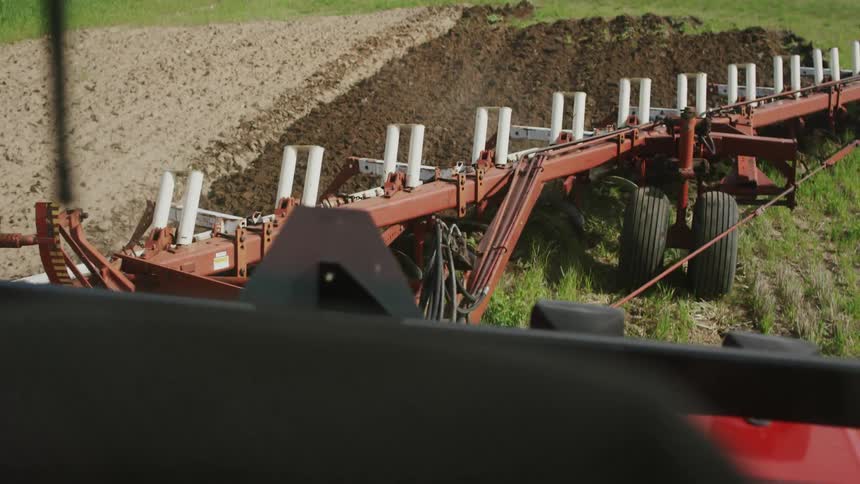 A farm tractor grades the soil on a farm