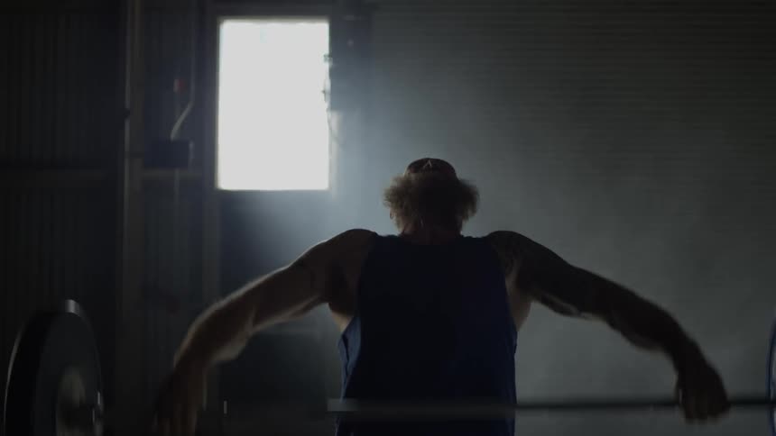 A bearded man lifts weights