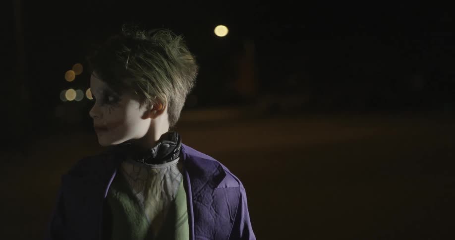 A child dressed in a joker costume looks around