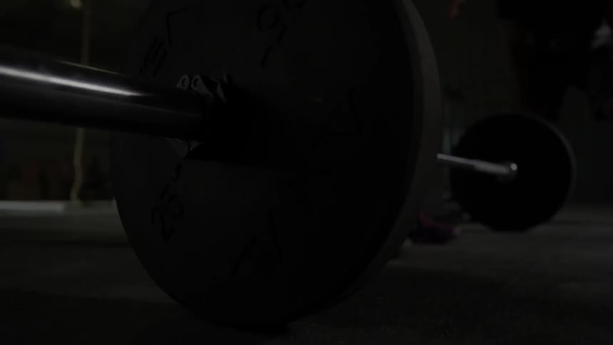 A woman drops a barbell to the floor