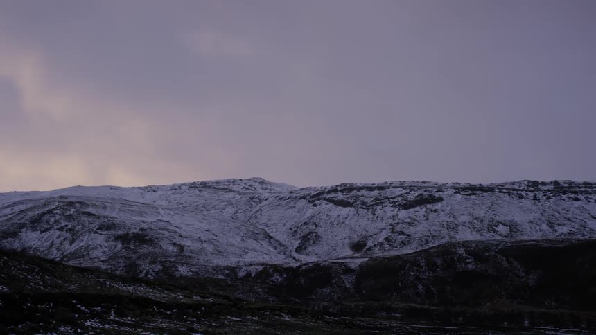 A snow covered mountain range at dusk