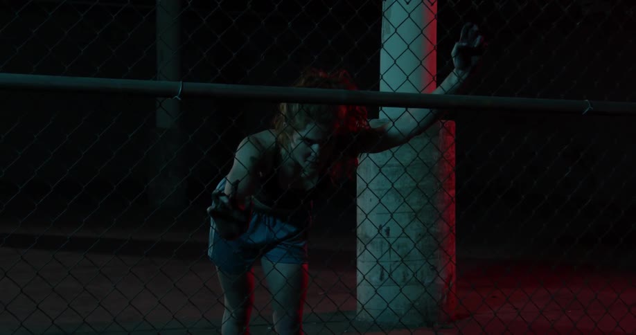 A woman breathes heavily while leaning against a chain link fence