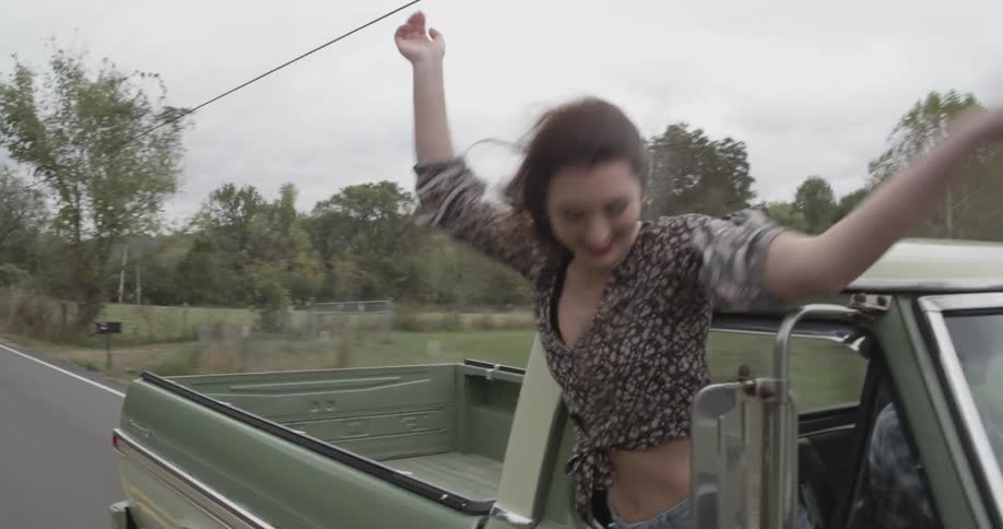 A woman is hanging out of the moving truck cheering