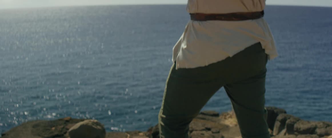 A man plays violin while overlooking the ocean