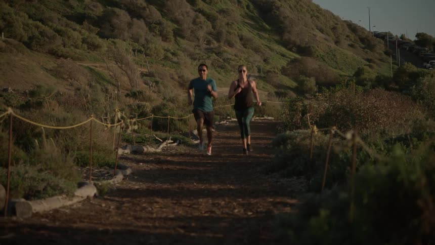 A man and a woman are running down a dirt road