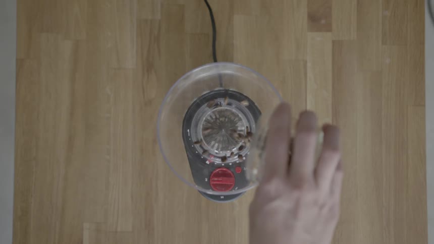 Person pouring coffee beans into a blender