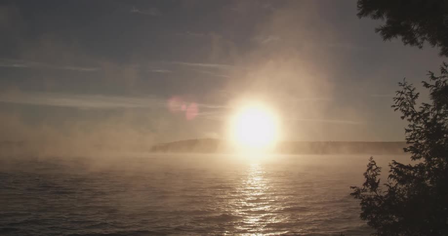 Fog rises off a lake at sunrise