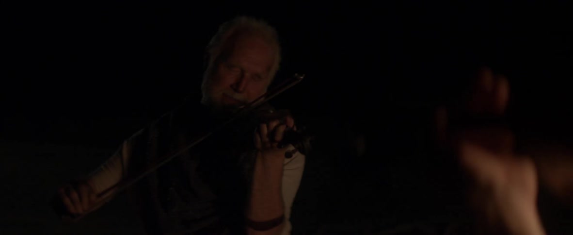 Two men play violins outside at night
