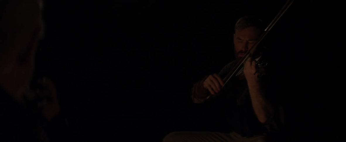 A man plays the violin at night time