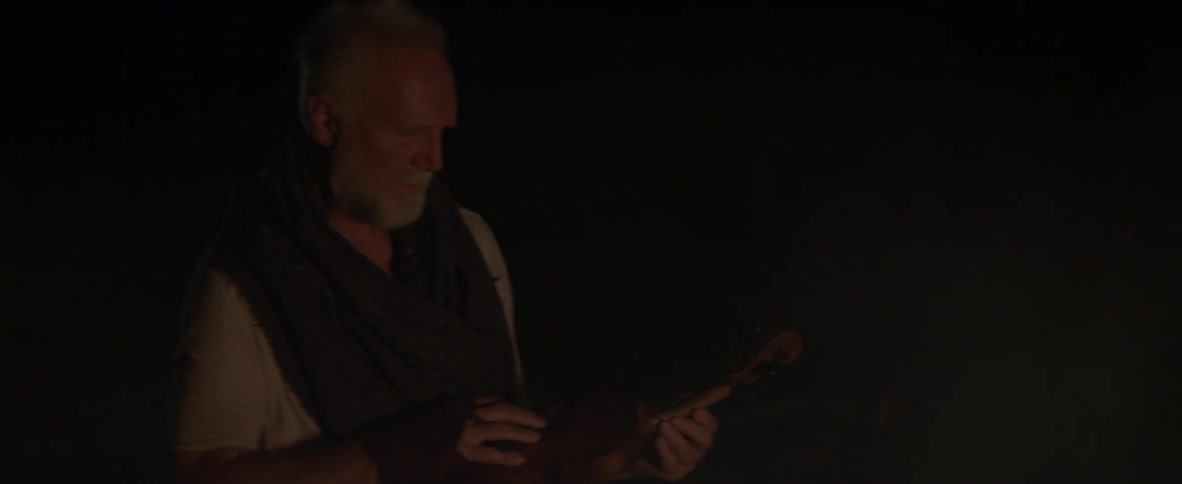 A man is examining his violin in the dark