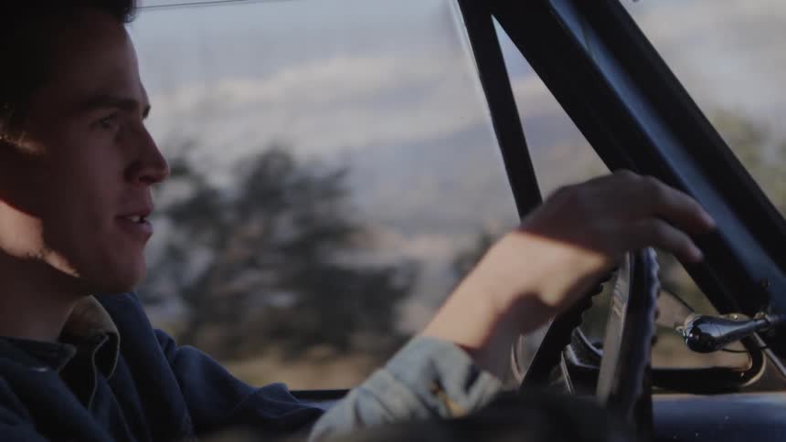 A man smiles while driving in the day time