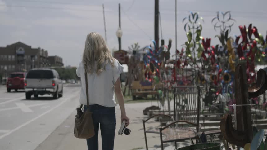 A woman is walking down the street carrying a camera