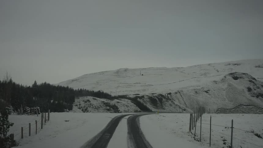 Traveling down a small snow covered road to a mountain range