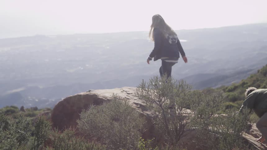Man and woman hiking up a rock