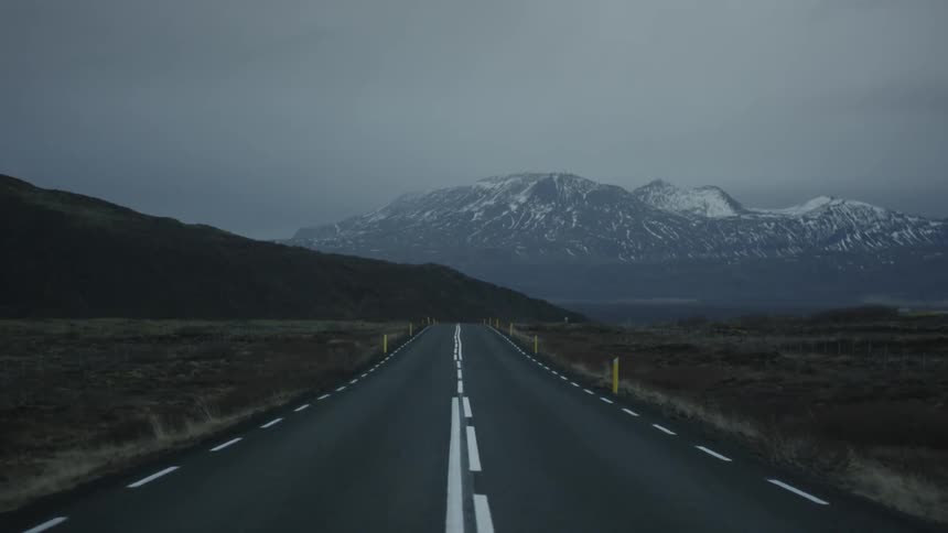 Driving down a road towards a snow covered mountain