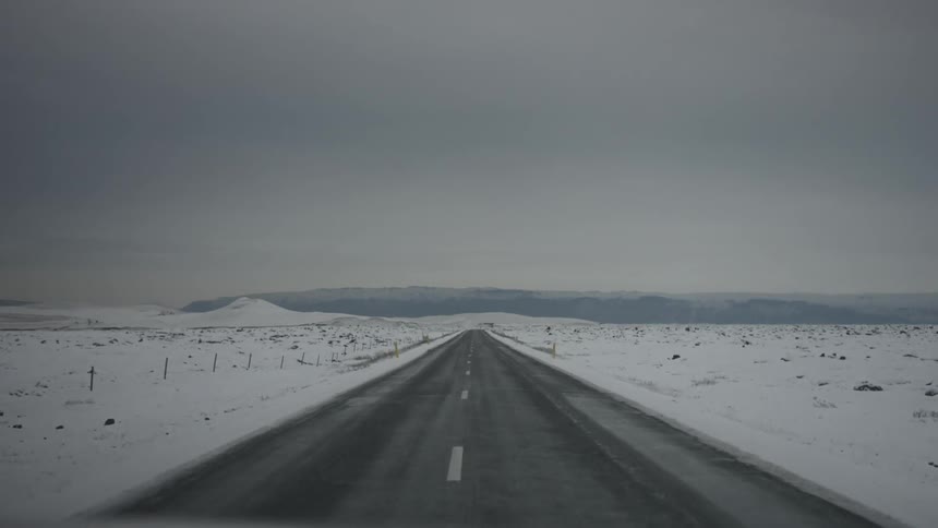 Driving down a road surrounded by snow covered ground