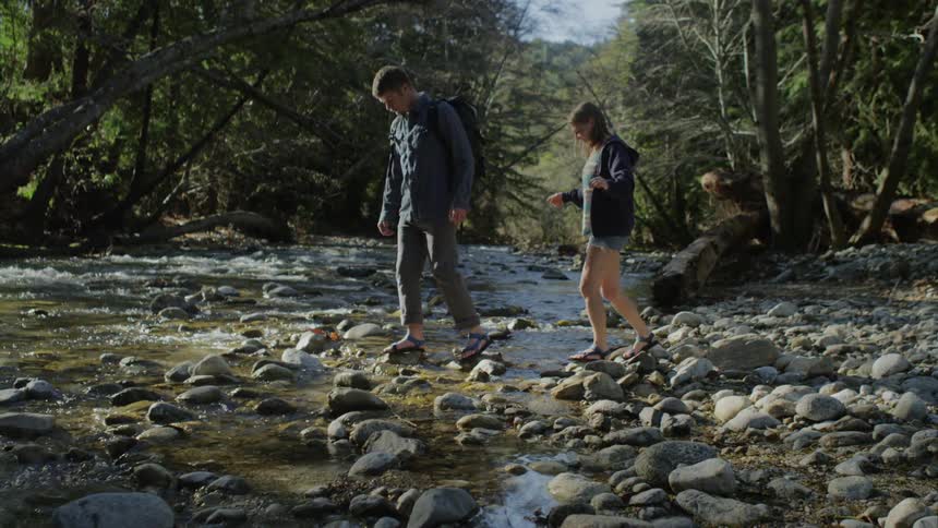 Man and woman step across a brook