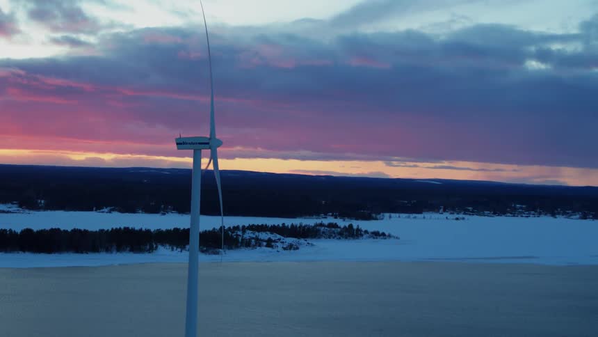 A wind turbine rotates at sunset
