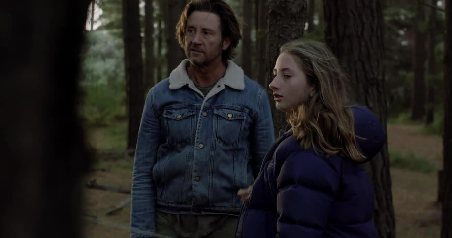 A man is showing a young girl how to shoot a bow and arrow