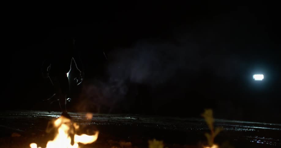 A person is tossing a television into a puddle of water near a fire