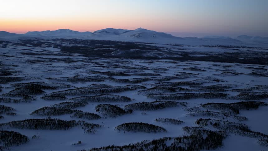 Hilly snow covered land at sunset