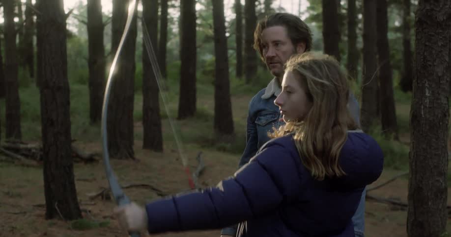 A woman cocks a bow and shoots
