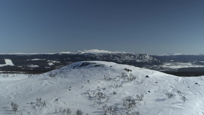 A snow covered mountain range is filmed by a drone