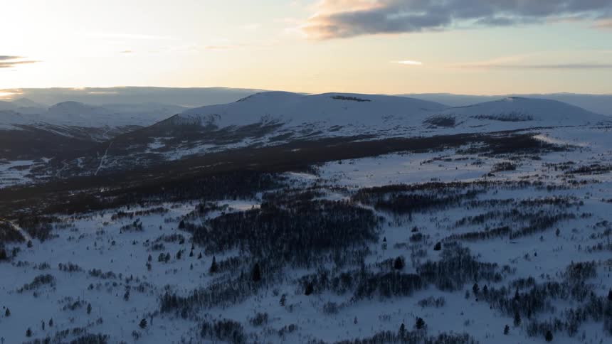 The sun sets over snowy mountains