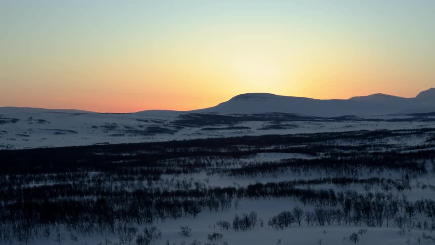 The sun sets over a snowy mountain