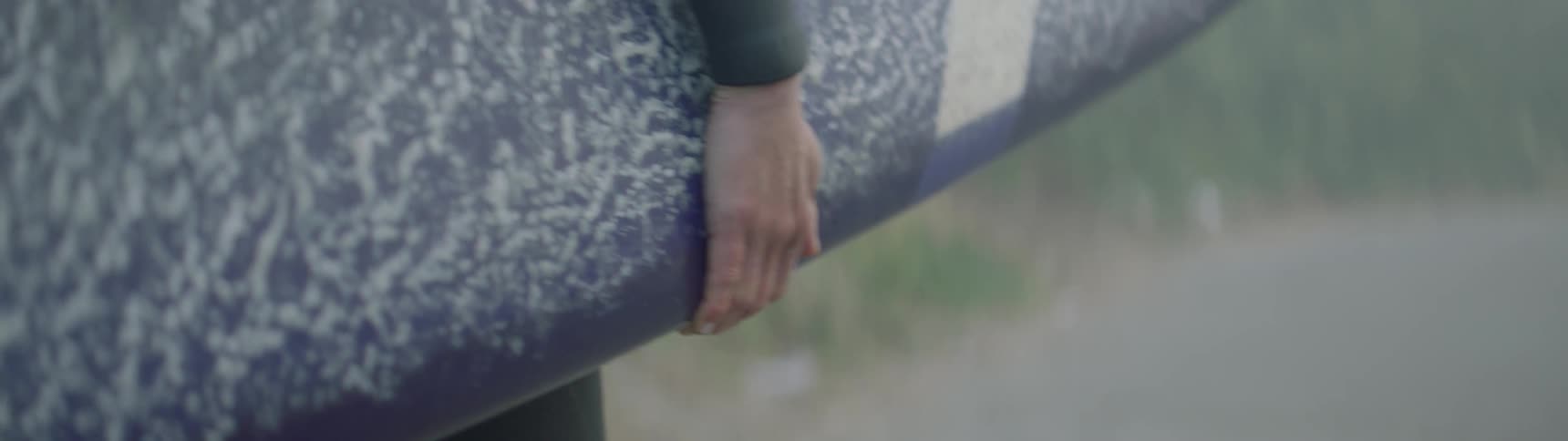 A surfer carries a surfboard outside