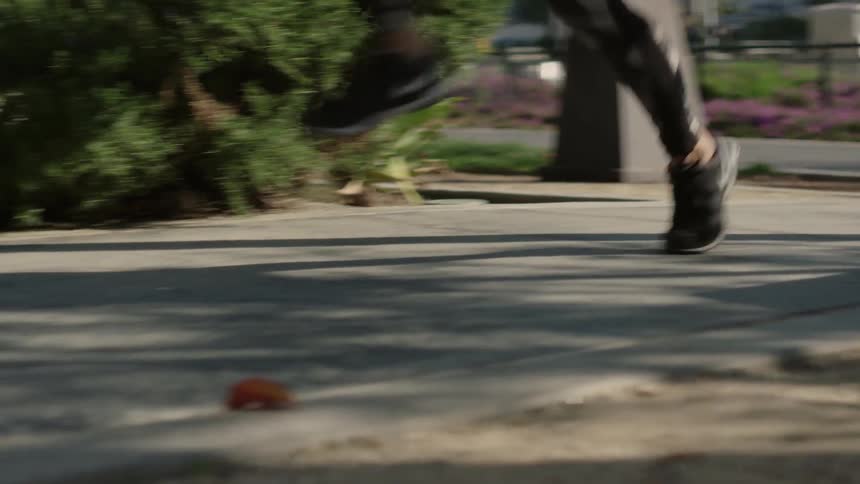 A woman jogs on a sidewalk and jumps