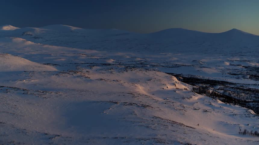 Snow covers mountains at sunset