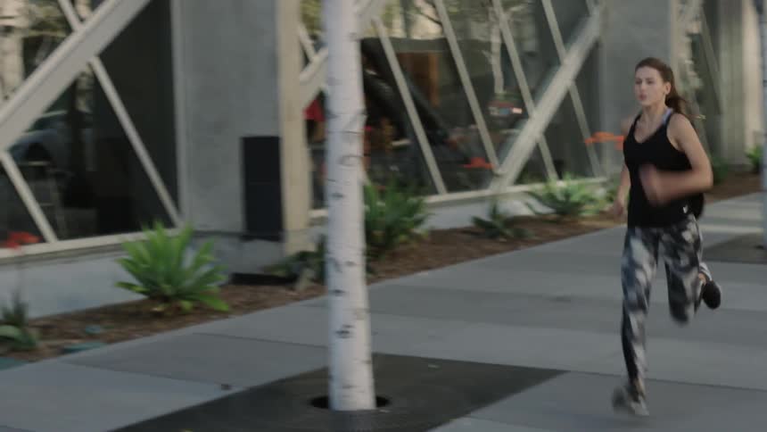 A woman is sprinting down the sidewalk
