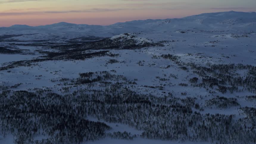 The sun sets over snowy mountains