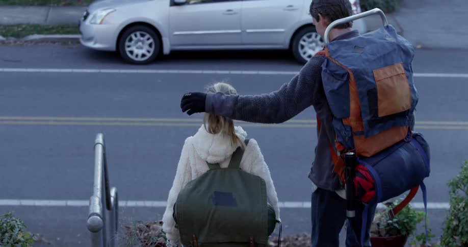 A father and daughter wearing backpacks walk down steps