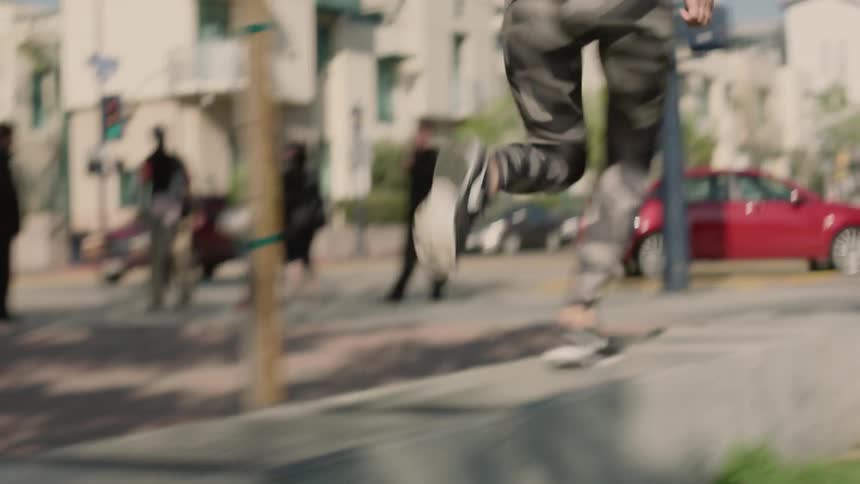 A female athlete runs along the top of a wall on a city street