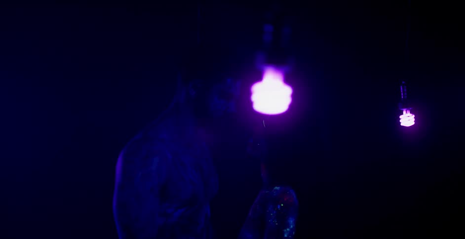 Two people embrace under some purple lights