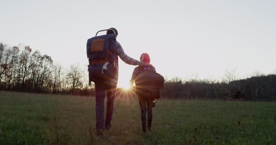 A man and child hike at sunset