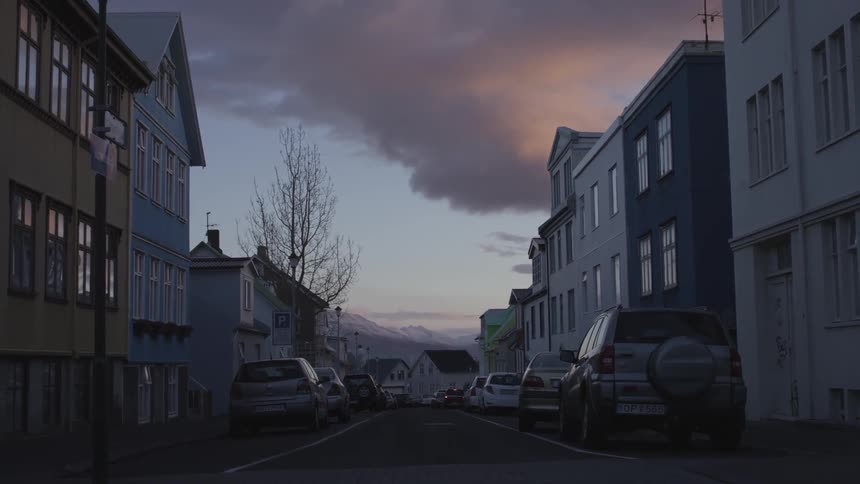 Cars line the street of a town at dusk