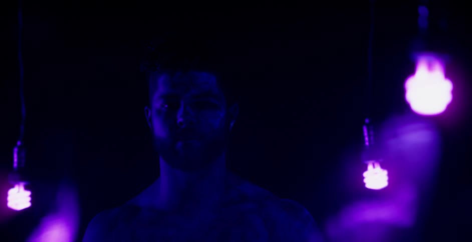 A man stands in a room with colored light bulbs