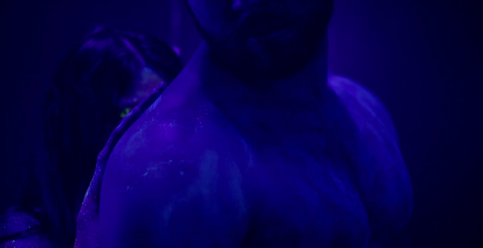 A woman and man wearing glitter paint embrace