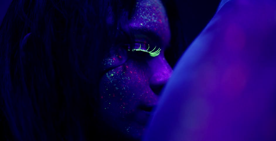 A woman with glowing face paint leans against a man