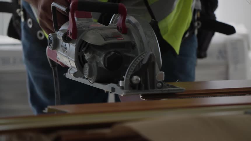 A worker is cutting boards with a saw